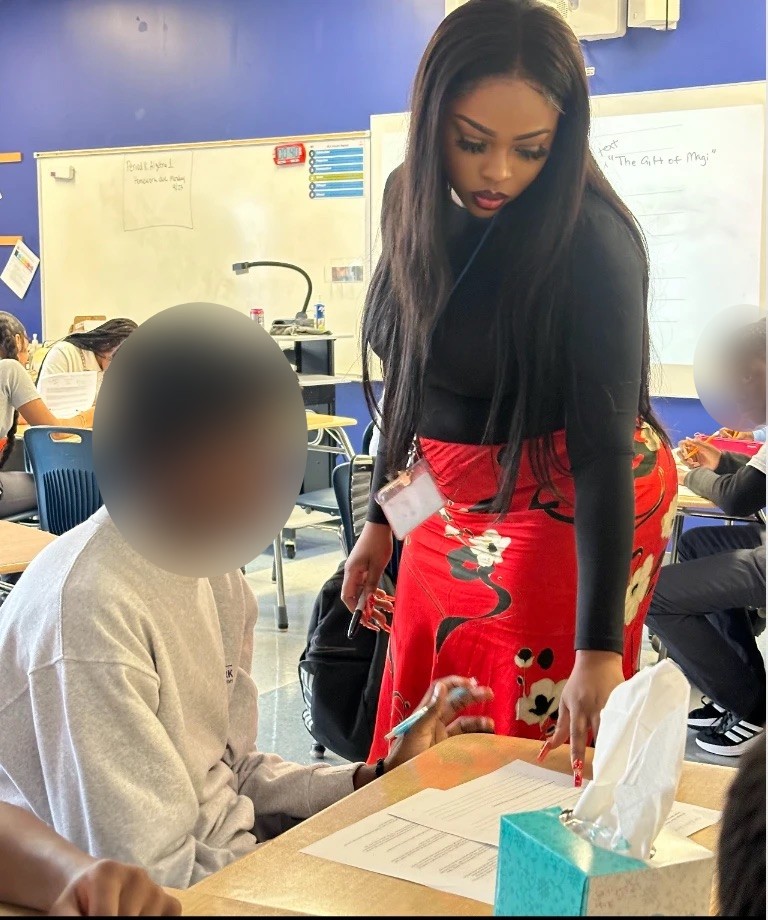 A teacher bending over to help a student with classwork at his desk