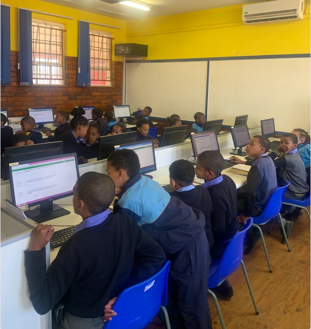 Students working at computers in a bright yellow computer lab